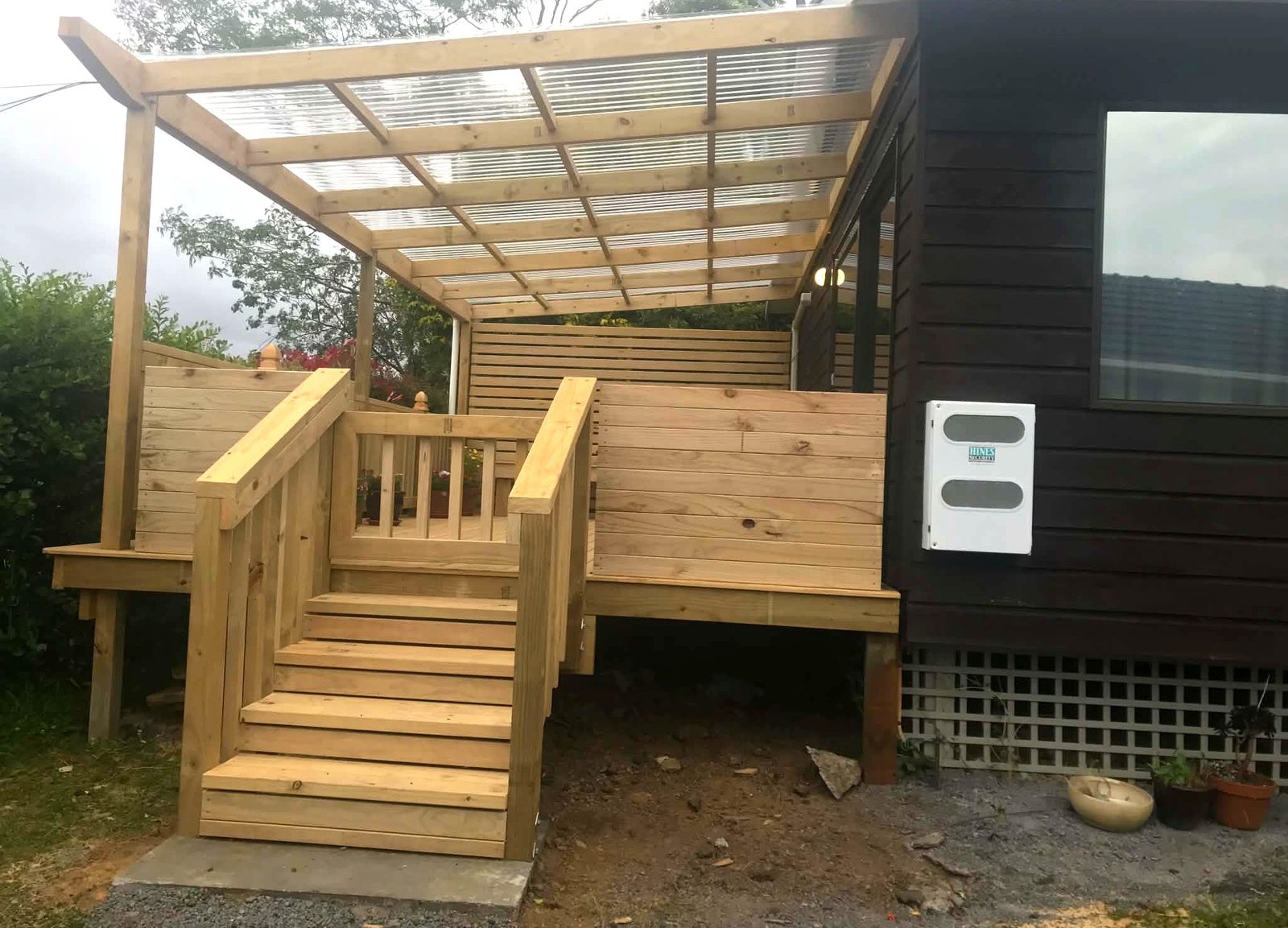Timber pergola with polycarbonate roof over a deck, with steps down to the garden